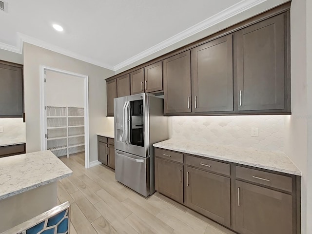 kitchen with tasteful backsplash, ornamental molding, light stone countertops, and stainless steel refrigerator with ice dispenser