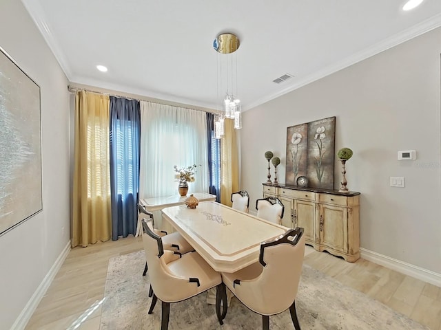 dining room featuring crown molding, a chandelier, and light hardwood / wood-style flooring