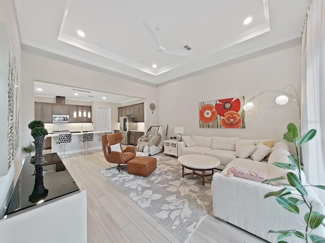 living room featuring a raised ceiling, ornamental molding, ceiling fan, and light hardwood / wood-style floors