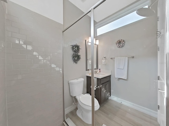 bathroom featuring vanity, wood-type flooring, tiled shower, and toilet