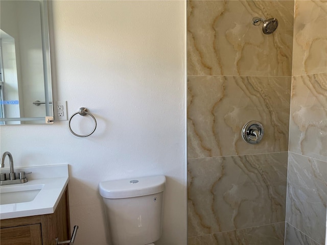 bathroom with vanity, a tile shower, and toilet