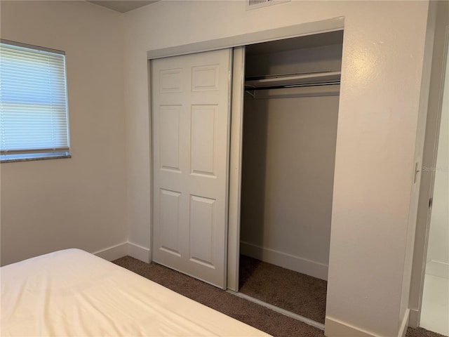 unfurnished bedroom featuring dark carpet and a closet