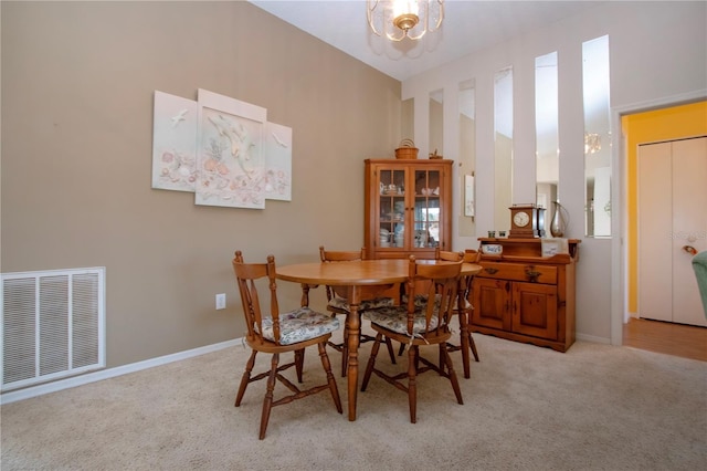 carpeted dining area with a chandelier and high vaulted ceiling