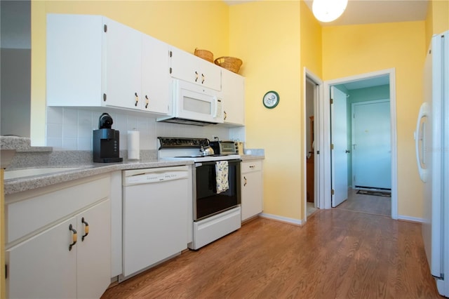 kitchen with white cabinetry, tasteful backsplash, wood-type flooring, vaulted ceiling, and white appliances