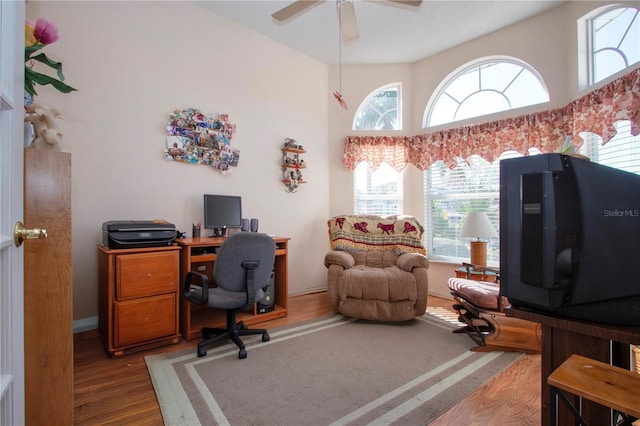 office with ceiling fan, a towering ceiling, and light hardwood / wood-style floors