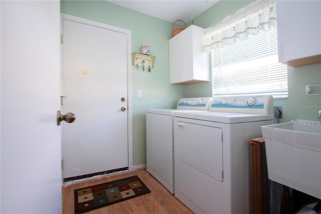 laundry room featuring cabinets, washing machine and dryer, sink, and light hardwood / wood-style flooring