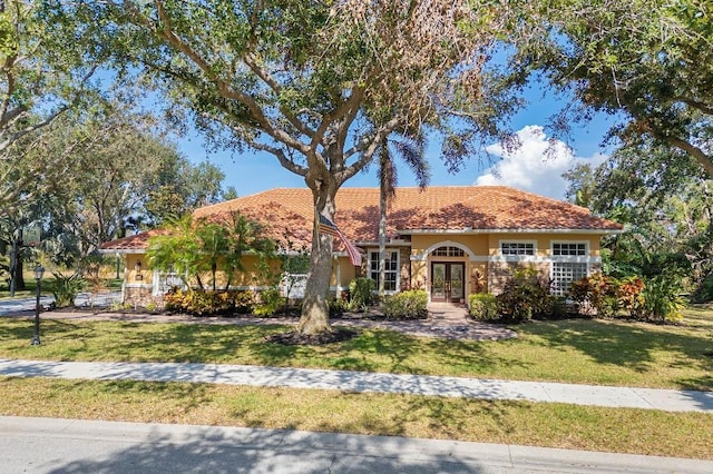 mediterranean / spanish house with a front yard and french doors