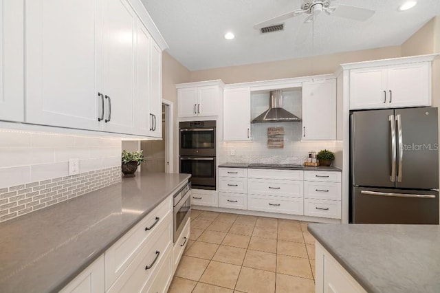 kitchen with tasteful backsplash, white cabinetry, appliances with stainless steel finishes, and wall chimney range hood