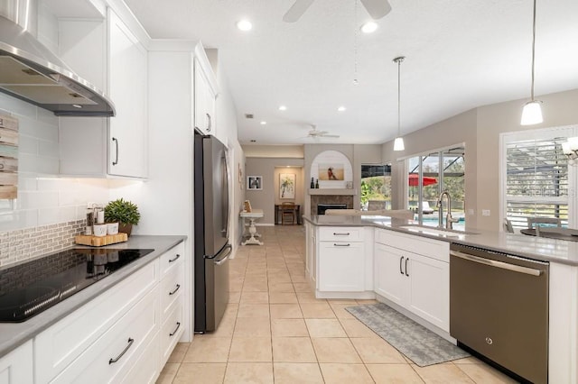 kitchen featuring wall chimney exhaust hood, sink, white cabinetry, decorative light fixtures, and appliances with stainless steel finishes