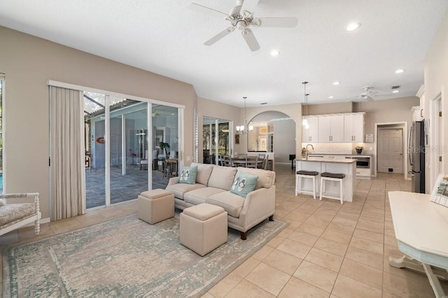 living room with sink, ceiling fan with notable chandelier, and light tile patterned floors