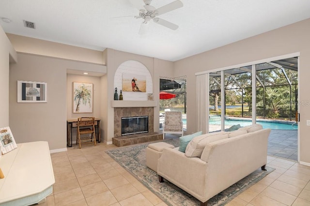 living room with a tile fireplace, light tile patterned flooring, and ceiling fan