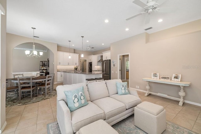 living room featuring light tile patterned floors and ceiling fan with notable chandelier