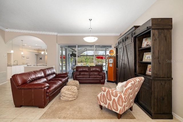 living room featuring sink, crown molding, a barn door, and light tile patterned flooring