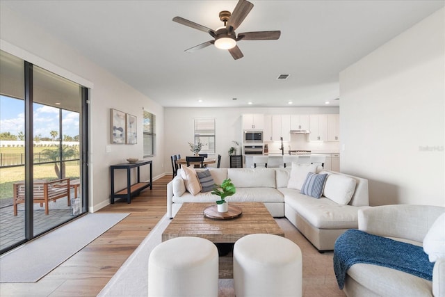 living room featuring ceiling fan and light hardwood / wood-style flooring