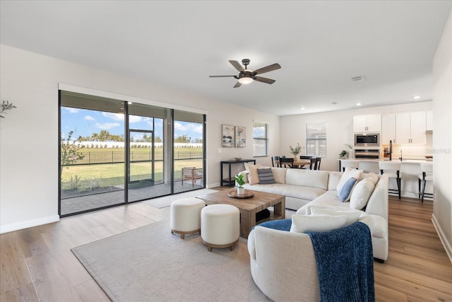 living room with ceiling fan and light hardwood / wood-style flooring