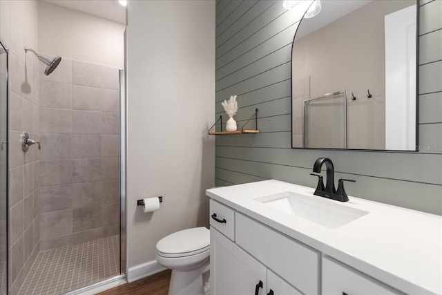 bathroom featuring hardwood / wood-style flooring, vanity, a shower with shower door, toilet, and wood walls