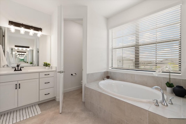 bathroom with tile patterned flooring, vanity, tiled tub, and toilet