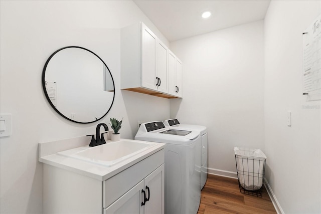 laundry room with dark wood-type flooring, cabinets, separate washer and dryer, and sink