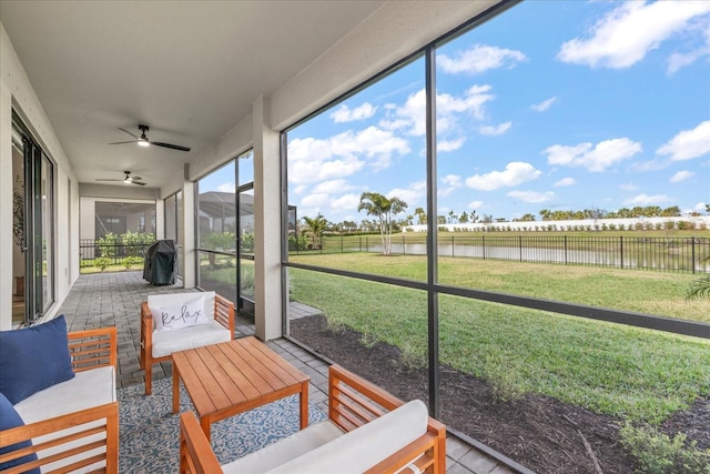 sunroom / solarium featuring ceiling fan and a water view