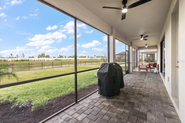 unfurnished sunroom featuring a rural view, ceiling fan, and a water view