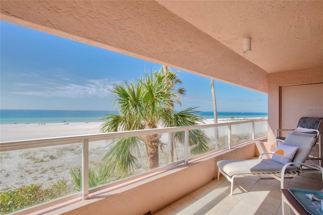 balcony with a water view and a view of the beach