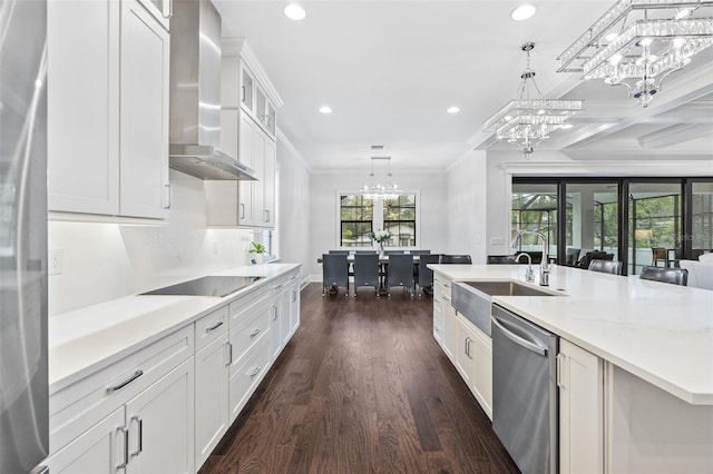 kitchen with wall chimney exhaust hood, white cabinetry, appliances with stainless steel finishes, and hanging light fixtures