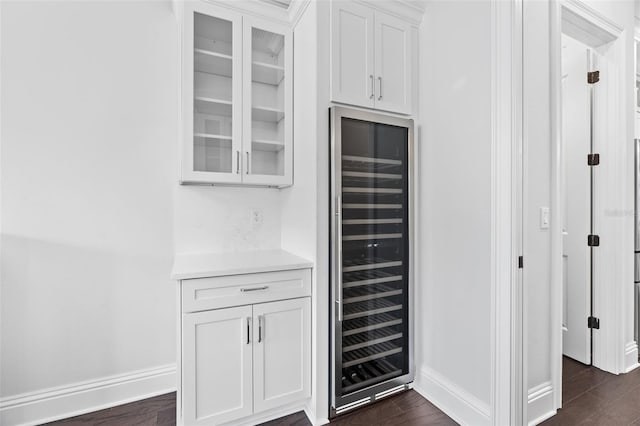 bar featuring white cabinetry, beverage cooler, and dark wood-type flooring