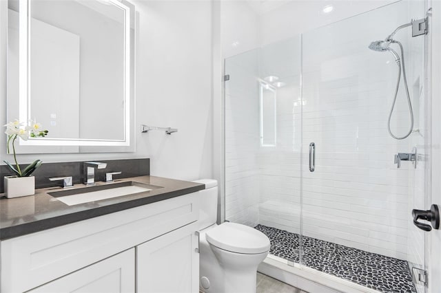 bathroom featuring a shower with door, vanity, and toilet