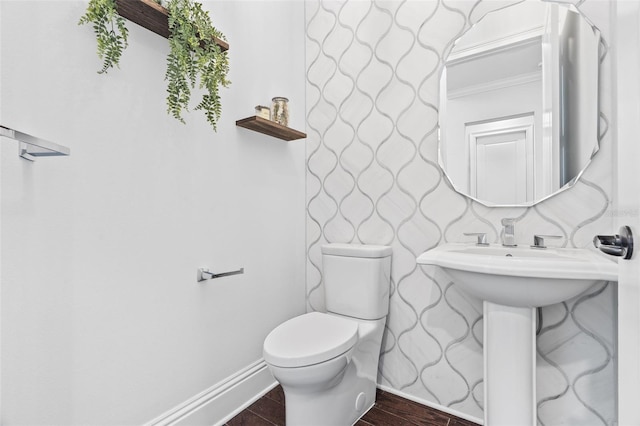 bathroom with hardwood / wood-style flooring, crown molding, and toilet