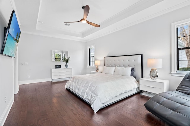 bedroom featuring ornamental molding, dark hardwood / wood-style floors, a raised ceiling, and multiple windows