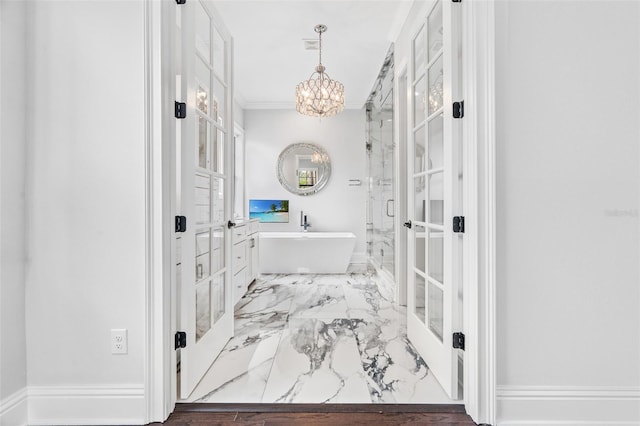 bathroom featuring crown molding, a tub, a chandelier, and french doors