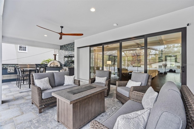 view of patio with an outdoor living space with a fire pit, ceiling fan, and an outdoor kitchen