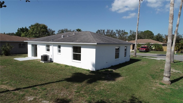 back of property with central AC unit and a lawn