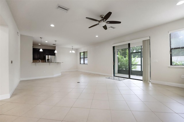 tiled empty room featuring ceiling fan with notable chandelier