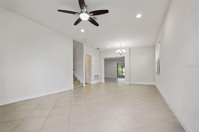 spare room with ceiling fan with notable chandelier and light tile patterned floors