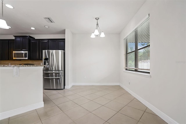 kitchen with light stone counters, light tile patterned floors, decorative light fixtures, and stainless steel appliances