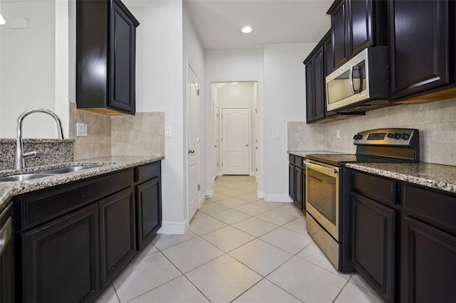 kitchen with appliances with stainless steel finishes, light stone countertops, sink, and light tile patterned floors