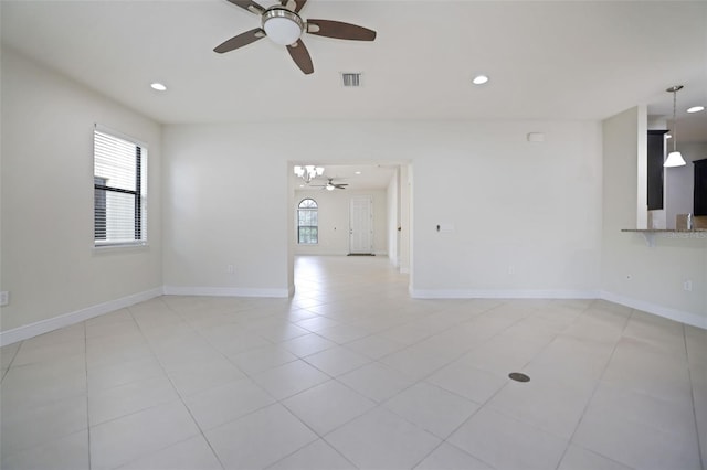 unfurnished room with ceiling fan with notable chandelier and light tile patterned flooring