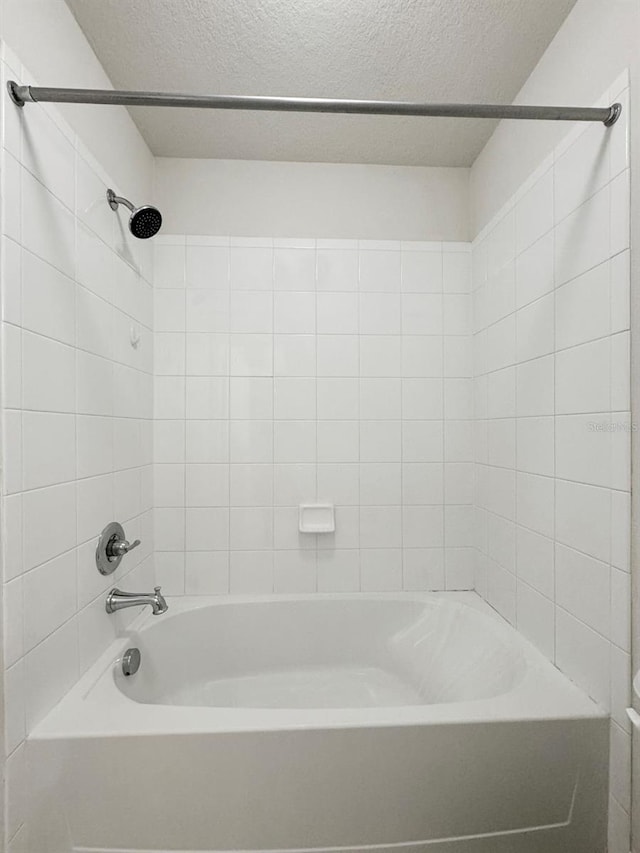 bathroom featuring tiled shower / bath and a textured ceiling