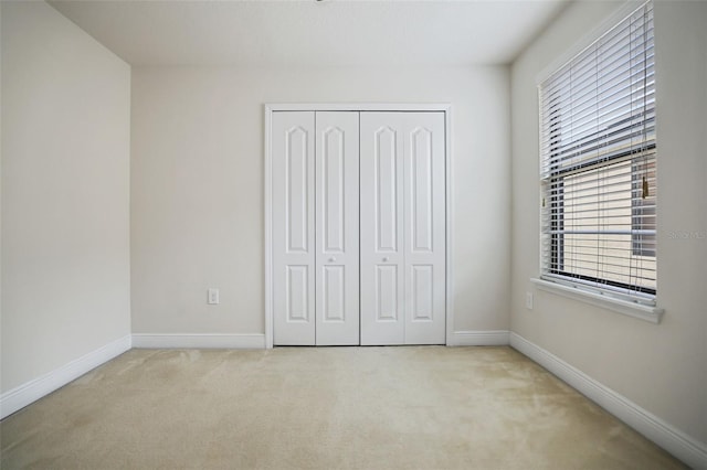 unfurnished bedroom with light carpet and a closet