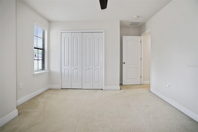 unfurnished bedroom with ceiling fan, a closet, and light carpet