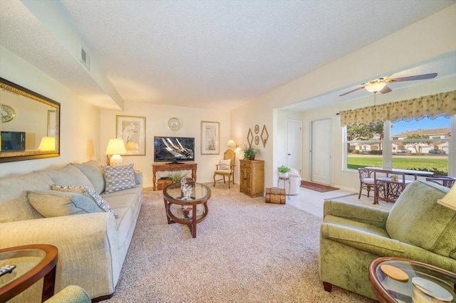 carpeted living room featuring ceiling fan and a textured ceiling