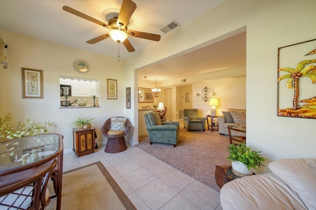 living room with ceiling fan with notable chandelier, a textured ceiling, and light tile patterned floors