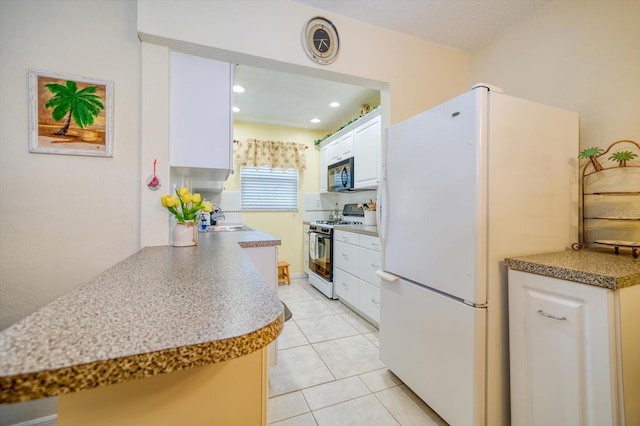 kitchen featuring sink, white cabinetry, gas stove, kitchen peninsula, and white fridge