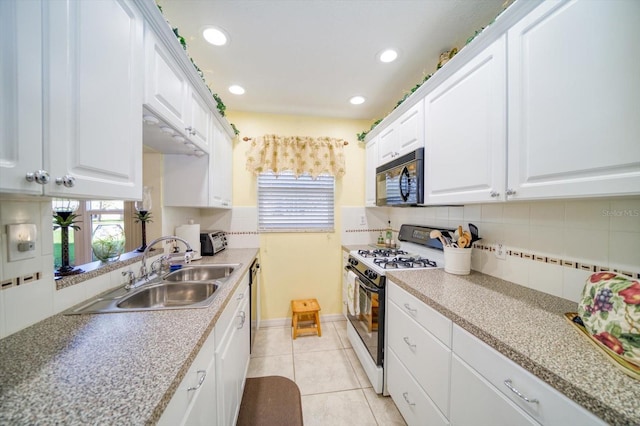 kitchen featuring tasteful backsplash, white gas range, sink, white cabinets, and light tile patterned floors