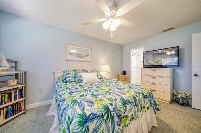 bedroom with ceiling fan, light carpet, and a textured ceiling