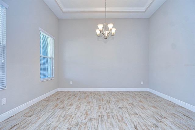 unfurnished room featuring an inviting chandelier, a raised ceiling, and light hardwood / wood-style flooring