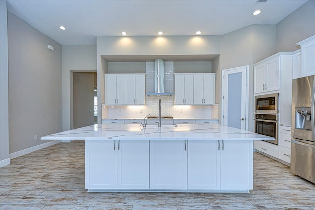 kitchen featuring a large island, stainless steel appliances, tasteful backsplash, white cabinets, and wall chimney exhaust hood