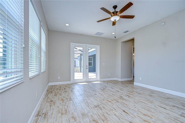 empty room with plenty of natural light, french doors, ceiling fan, and light wood-type flooring