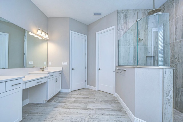 bathroom featuring tiled shower and vanity